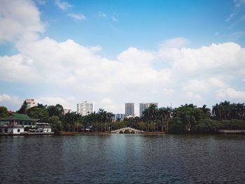 Scenic view of river by buildings against sky