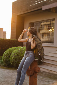 Beautiful young woman looking away leaning against fire hydrant 