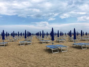 Panoramic view of lounge chairs on beach against sky