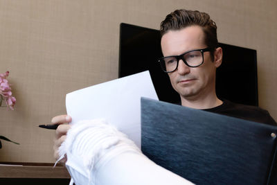 Portrait of young man holding eyeglasses at home