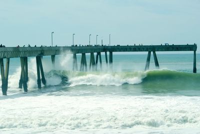 Water splashing in sea against pacifica pier and sky