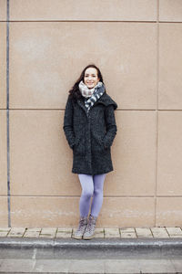 Portrait of young woman standing on wall