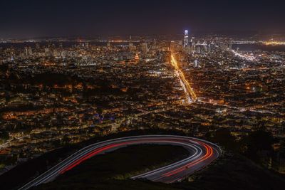 High angle view of illuminated city by buildings at night