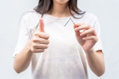 Midsection of woman holding hands against white background