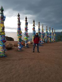 Rear view of people standing at beach against sky