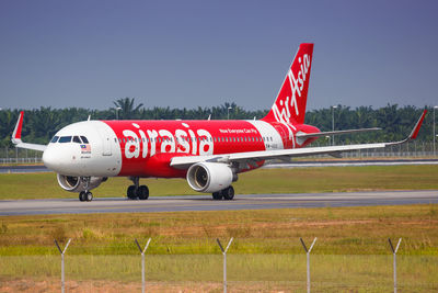 Red airplane on airport runway against clear sky