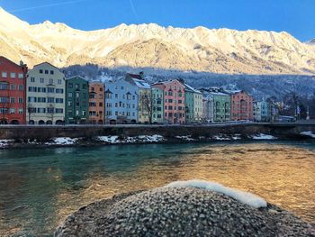 Buildings by snowcapped mountains against sky