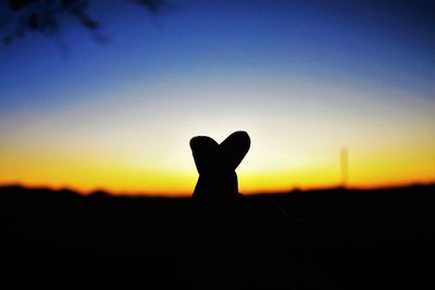 Silhouette hand against clear sky during sunset