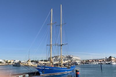 Boats in sea against clear blue sky