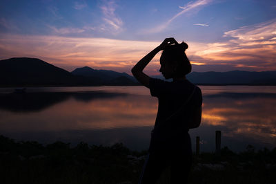 Silhouette woman standing by tree against sky during sunset