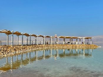 View of swimming pool by sea against clear blue sky