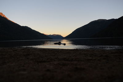 Scenic view of lake against clear sky during sunset