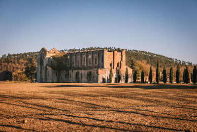 Built structure on landscape against clear blue sky