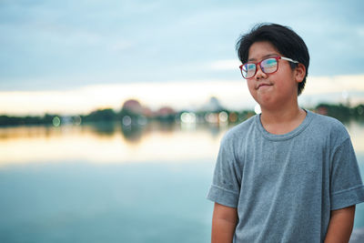 Portrait of teenage boy standing against sky