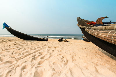 Boat moored on beach against clear sky