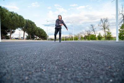 Man skating on road against sky