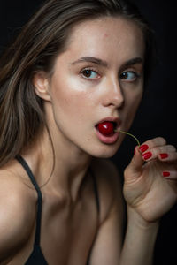 Close-up portrait of a beautiful young woman over black background