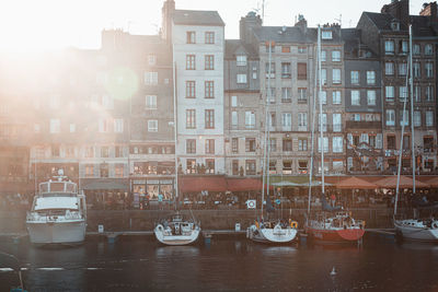 Sailboats moored on canal by buildings in city