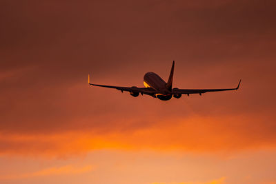 Low angle view of airplane flying against sky during sunset