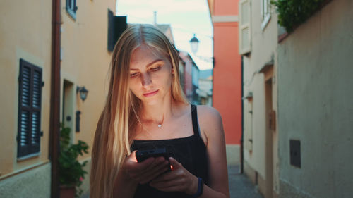 Young woman looking away while standing on mobile phone