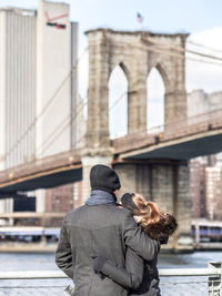 Rear view of people on bridge in city during winter