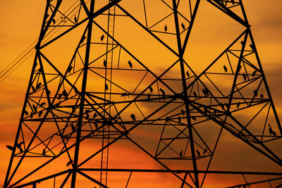 Low angle view of power lines against sky during sunset