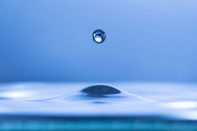 Close-up of water drop against blue sky