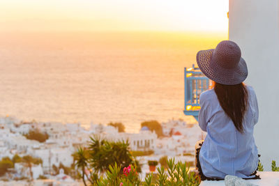 Rear view of woman standing by sea against sky