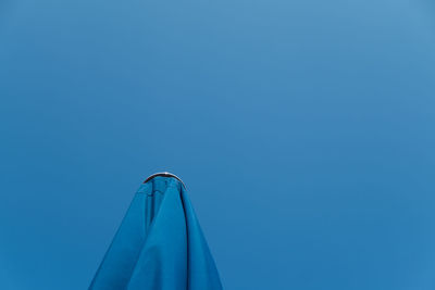 Low angle view of blue umbrella against clear sky on sunny day