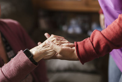 Caregiver holding senior woman's hand at home