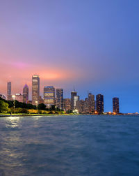 Illuminated buildings in city against sky during sunset