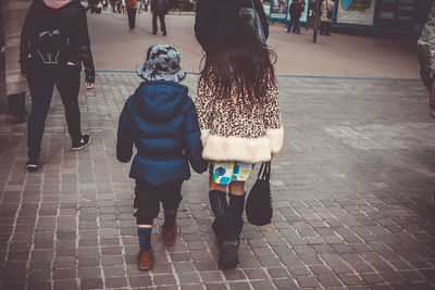 Rear view of couple walking on sidewalk