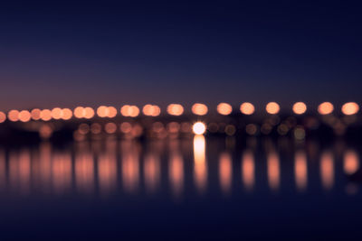 Defocused image of illuminated lights in calm river at night