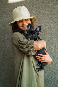 Woman holding a dog wearing hat