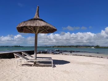 Deck chairs on beach against sky