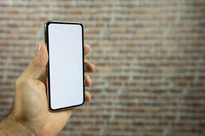 Midsection of man holding mobile phone against wall