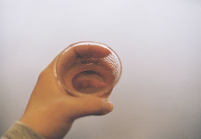 Close-up of hand holding candle against white background