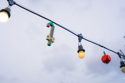 Low angle view of light bulbs hanging against sky