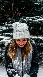 Close-up of smiling woman playing with snow