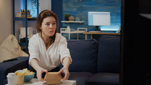 Young woman using phone while sitting on sofa