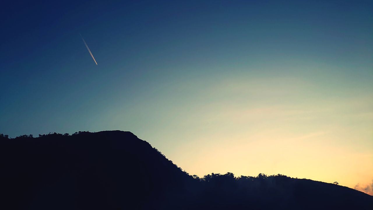 sky, horizon, dawn, silhouette, mountain, beauty in nature, scenics - nature, nature, sunrise, environment, cloud, tranquility, landscape, morning, tranquil scene, sunlight, no people, astronomical object, travel, mountain range, sun, outdoors, blue, land, travel destinations, idyllic, copy space, non-urban scene, light, afterglow