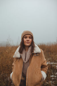 Portrait of beautiful woman standing in field during winter