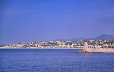 Scenic view of sea and buildings against clear blue sky