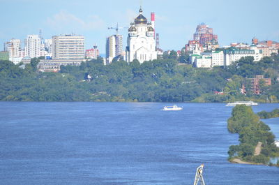 Sailboats in sea against buildings in city