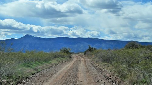 Dirt road along landscape against sky