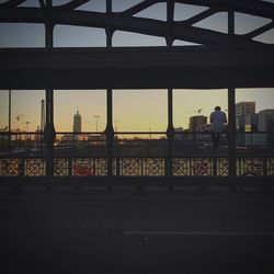 Silhouette of man sitting on bridge