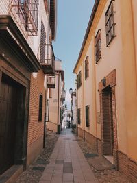 Walkway amidst buildings in city against clear sky