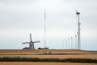 Windmills on field against sky