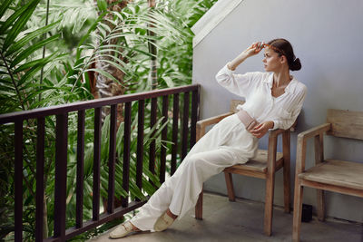 Side view of woman sitting on railing