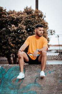 Portrait of young man sitting on footpath